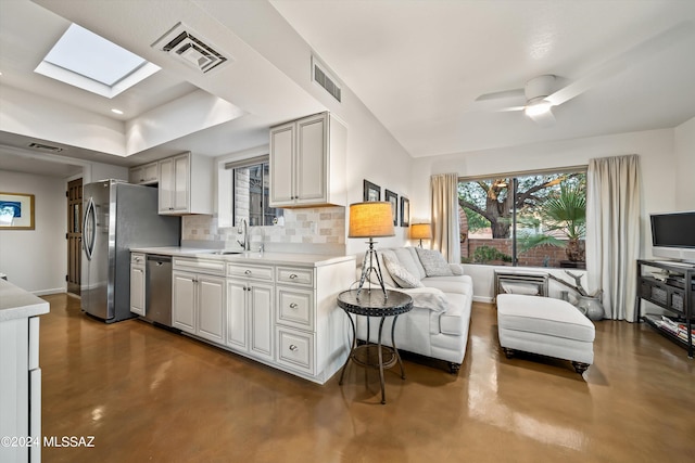 kitchen with backsplash, ceiling fan, sink, a skylight, and stainless steel appliances