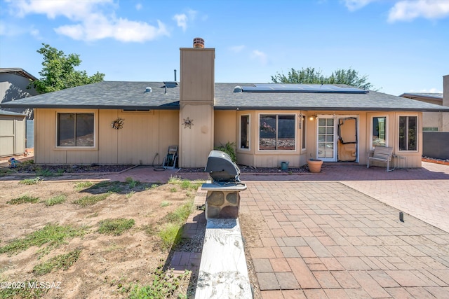 rear view of property with solar panels and a patio area