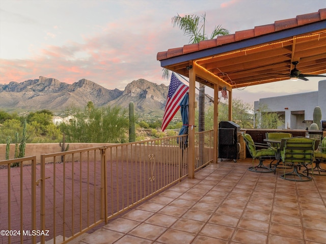 patio terrace at dusk featuring a mountain view, a grill, and ceiling fan