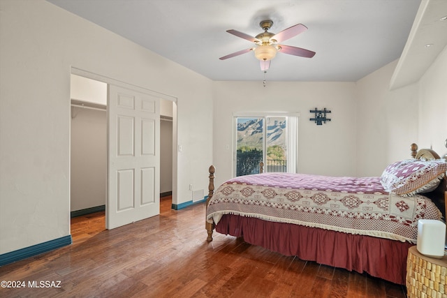 bedroom with dark wood-type flooring, ceiling fan, access to exterior, a spacious closet, and a closet