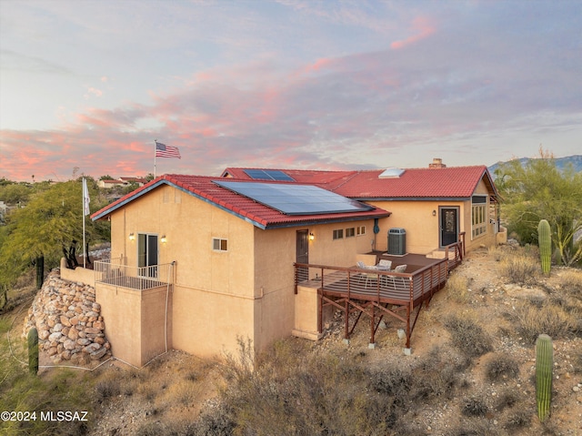 back house at dusk featuring outdoor lounge area and solar panels