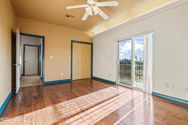 unfurnished bedroom featuring hardwood / wood-style floors, access to exterior, ceiling fan, and a closet