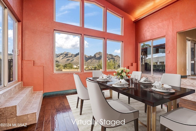 dining area with a mountain view, hardwood / wood-style flooring, and a towering ceiling