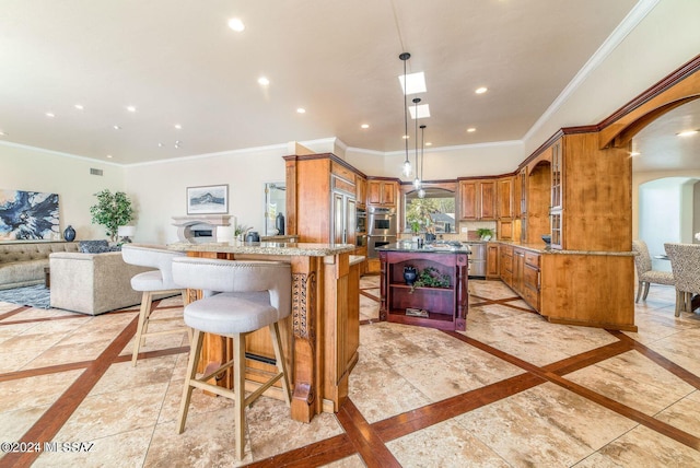 kitchen with a center island, pendant lighting, appliances with stainless steel finishes, ornamental molding, and a kitchen breakfast bar