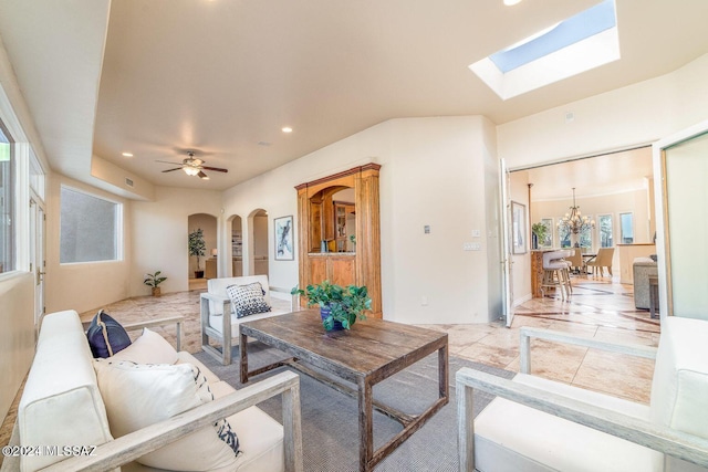 living room with ceiling fan with notable chandelier and a skylight