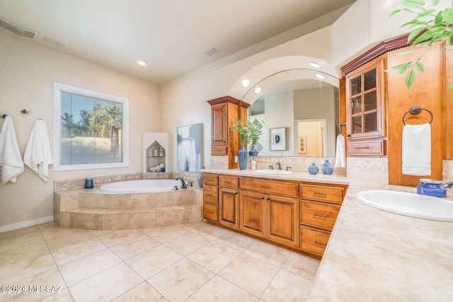 bathroom featuring tile patterned floors, vanity, and tiled bath