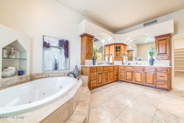 bathroom featuring tile patterned floors, a relaxing tiled tub, and vanity