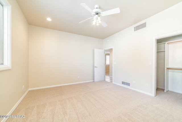 unfurnished bedroom with a closet, light colored carpet, multiple windows, and ceiling fan