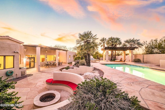 pool at dusk featuring an outdoor fire pit, a patio, and a pergola