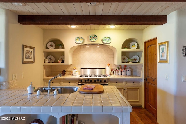 kitchen with dark hardwood / wood-style flooring, a breakfast bar, high end stove, sink, and tile counters