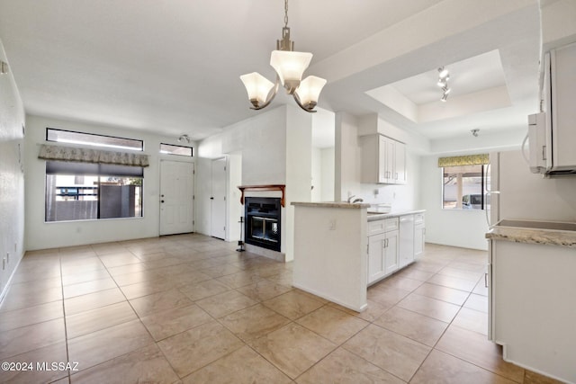 kitchen featuring white cabinetry, light tile patterned flooring, pendant lighting, and a tray ceiling