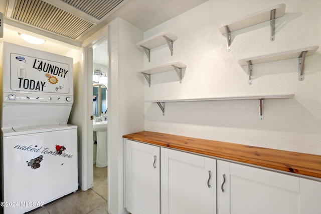 clothes washing area featuring stacked washer and dryer and light tile patterned flooring