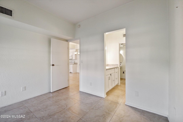 unfurnished bedroom featuring light tile patterned floors and ensuite bathroom