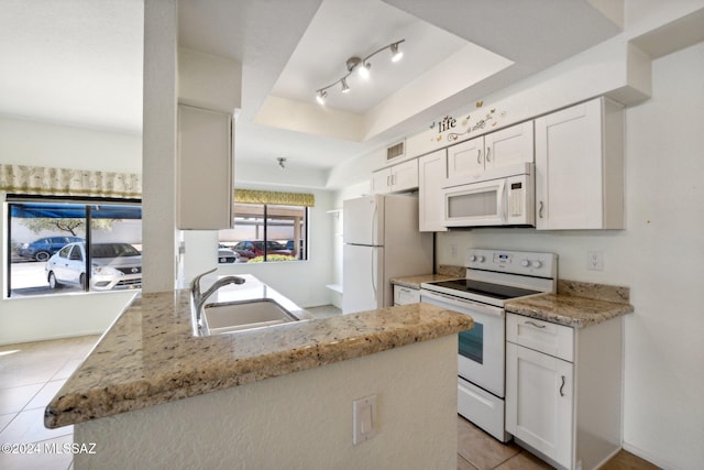 kitchen featuring white cabinets, kitchen peninsula, sink, light stone countertops, and white appliances