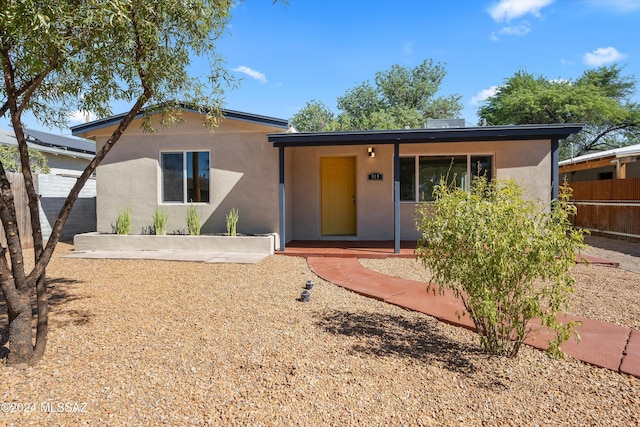 ranch-style house featuring stucco siding and fence