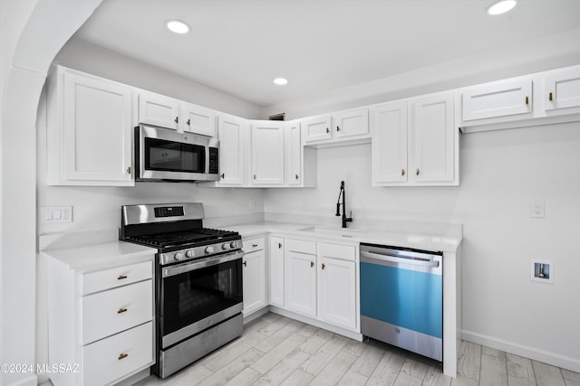 kitchen featuring white cabinets, light hardwood / wood-style floors, sink, and appliances with stainless steel finishes