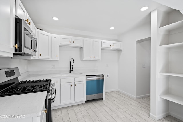 kitchen featuring white cabinetry, sink, light hardwood / wood-style floors, and appliances with stainless steel finishes