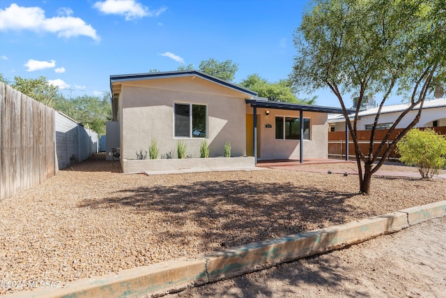 view of front of house featuring fence private yard, stucco siding, and a patio area