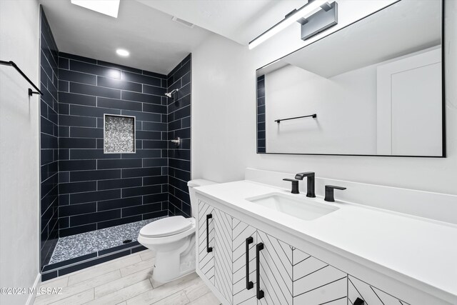 bathroom featuring tiled shower, vanity, and toilet