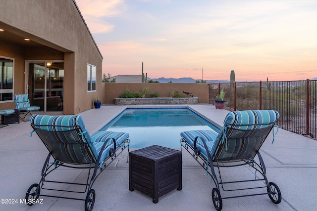 pool at dusk with a patio area