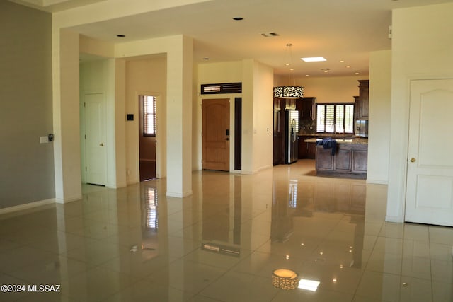 interior space with stainless steel refrigerator, dark brown cabinetry, light tile patterned floors, and a kitchen island