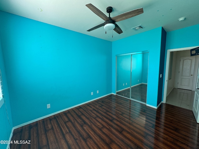 unfurnished bedroom with ceiling fan, dark wood-type flooring, and a closet