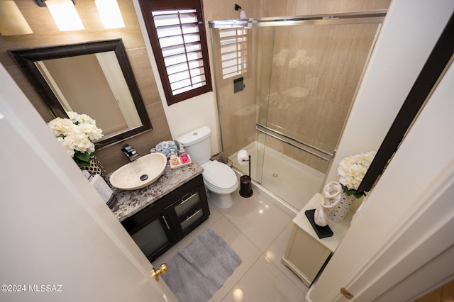 bathroom featuring tile patterned flooring, a shower with door, vanity, and toilet