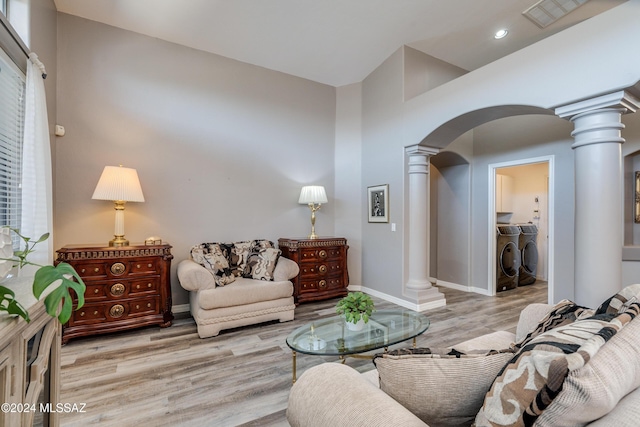 living area featuring wood finished floors, visible vents, ornate columns, arched walkways, and washer and dryer