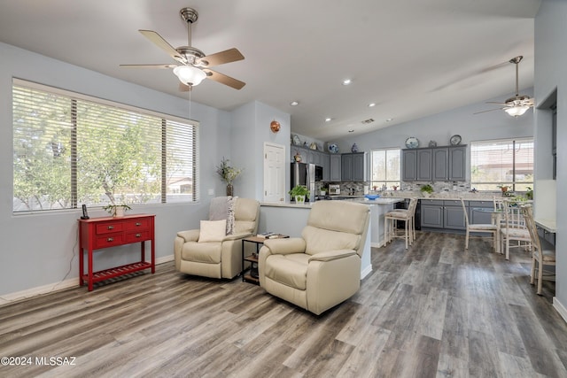 living area featuring vaulted ceiling, wood finished floors, baseboards, and ceiling fan