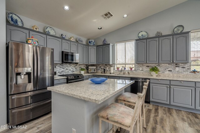 kitchen featuring appliances with stainless steel finishes, sink, vaulted ceiling, and a kitchen island