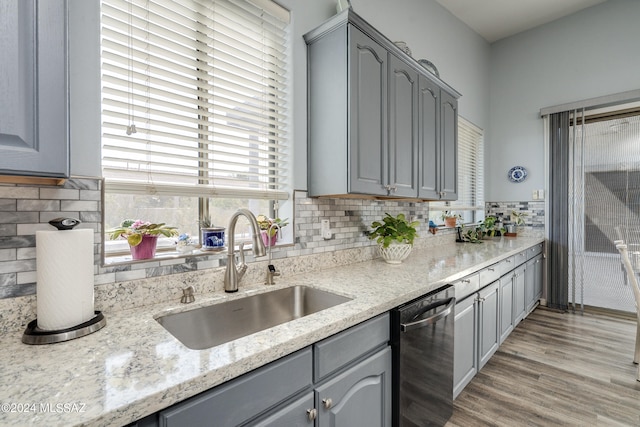 kitchen with gray cabinets, dishwasher, light stone countertops, and sink