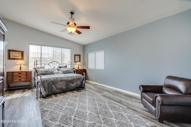 bedroom with lofted ceiling, wood finished floors, baseboards, and ceiling fan