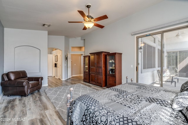 bedroom with visible vents, ceiling fan, wood finished floors, arched walkways, and access to exterior