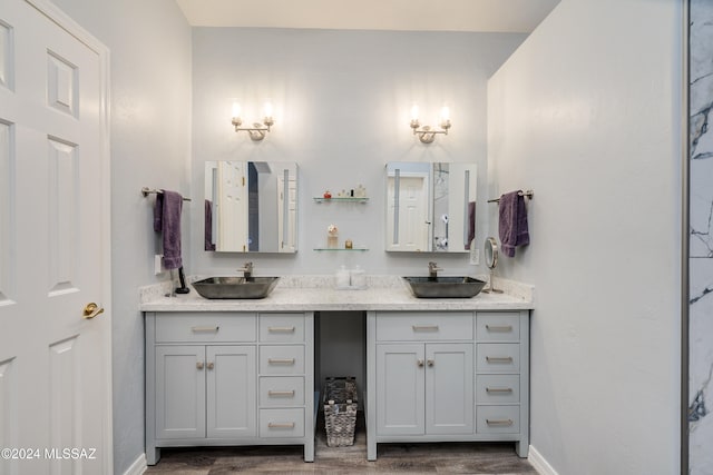 bathroom with a sink, baseboards, wood finished floors, and double vanity