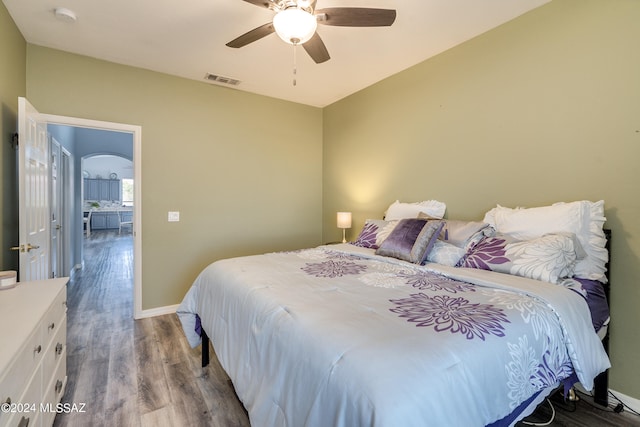 bedroom with visible vents, wood finished floors, arched walkways, baseboards, and ceiling fan