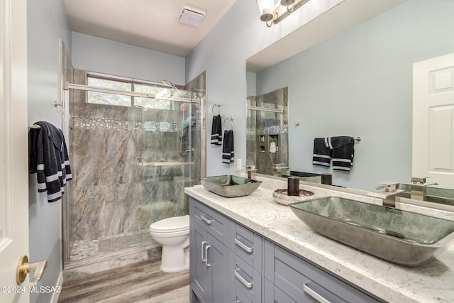 bathroom featuring vanity, wood-type flooring, a shower with shower door, and toilet