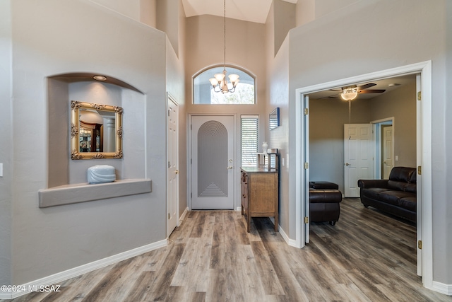 entrance foyer featuring hardwood / wood-style flooring, ceiling fan with notable chandelier, and a towering ceiling