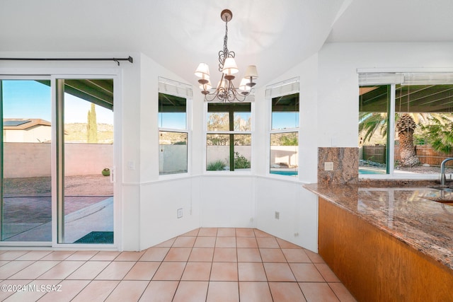 interior space featuring light tile patterned flooring, vaulted ceiling, and an inviting chandelier