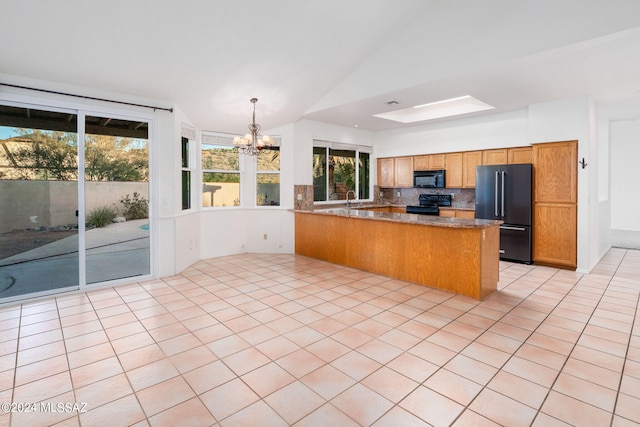 kitchen with vaulted ceiling, light tile patterned flooring, kitchen peninsula, black appliances, and a chandelier