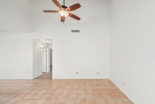 spare room with a towering ceiling, ceiling fan, and light tile patterned floors