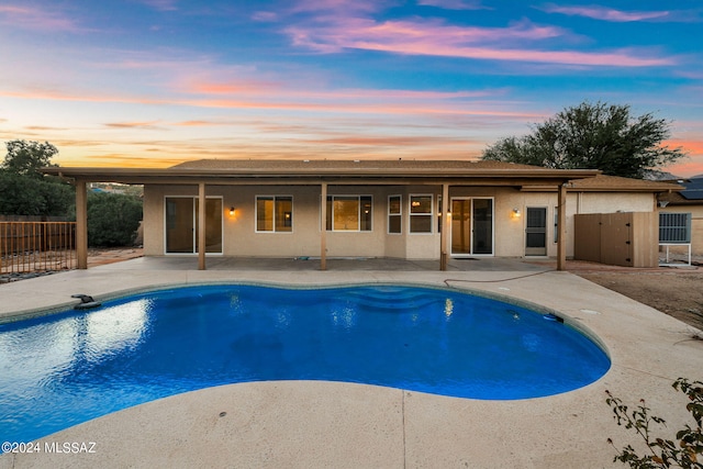 pool at dusk featuring a patio