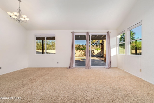 carpeted spare room featuring an inviting chandelier and lofted ceiling