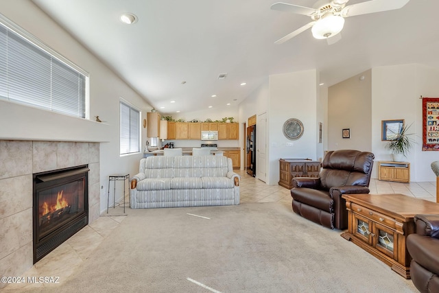 tiled living room with vaulted ceiling, ceiling fan, and a tiled fireplace