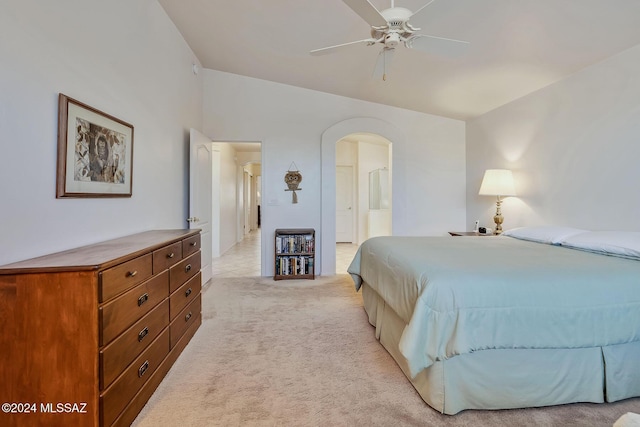 bedroom featuring vaulted ceiling, ceiling fan, light colored carpet, and ensuite bath