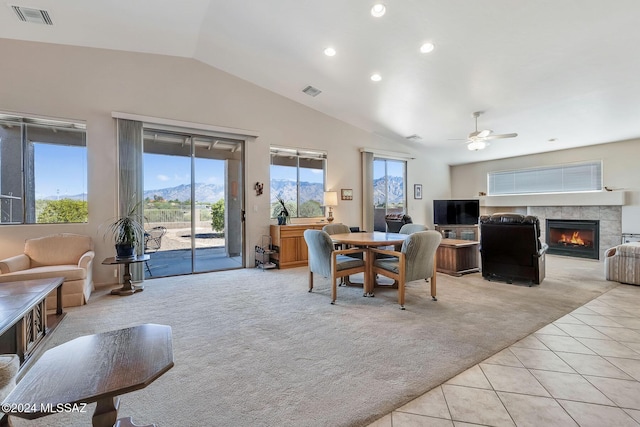 carpeted dining space with ceiling fan, lofted ceiling, and a tiled fireplace