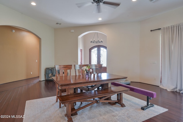 dining area with ceiling fan with notable chandelier, dark wood-type flooring, and french doors