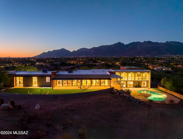 view of front of house with a patio, an outdoor pool, and a mountain view