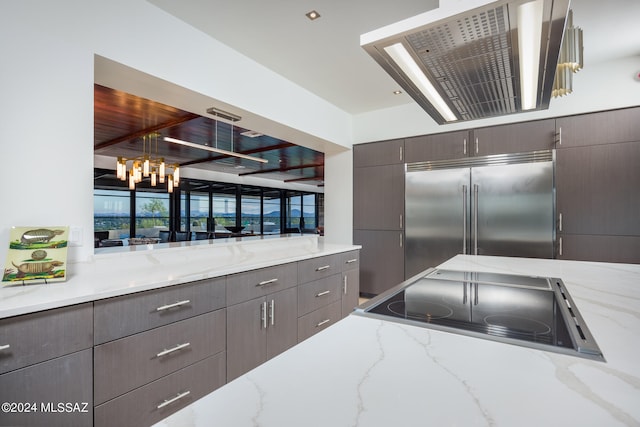 kitchen featuring black range, light stone countertops, a chandelier, and built in fridge