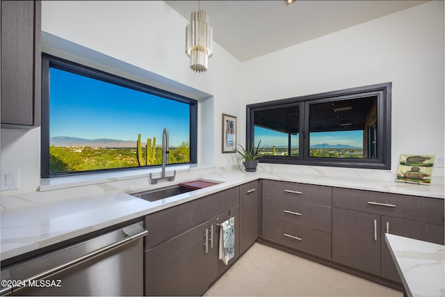 kitchen featuring light stone counters, dishwasher, a mountain view, decorative light fixtures, and sink