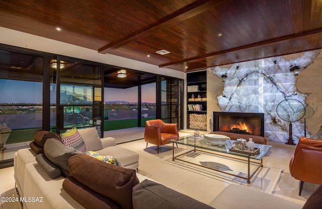 living room featuring built in features, beamed ceiling, a large fireplace, and wooden ceiling